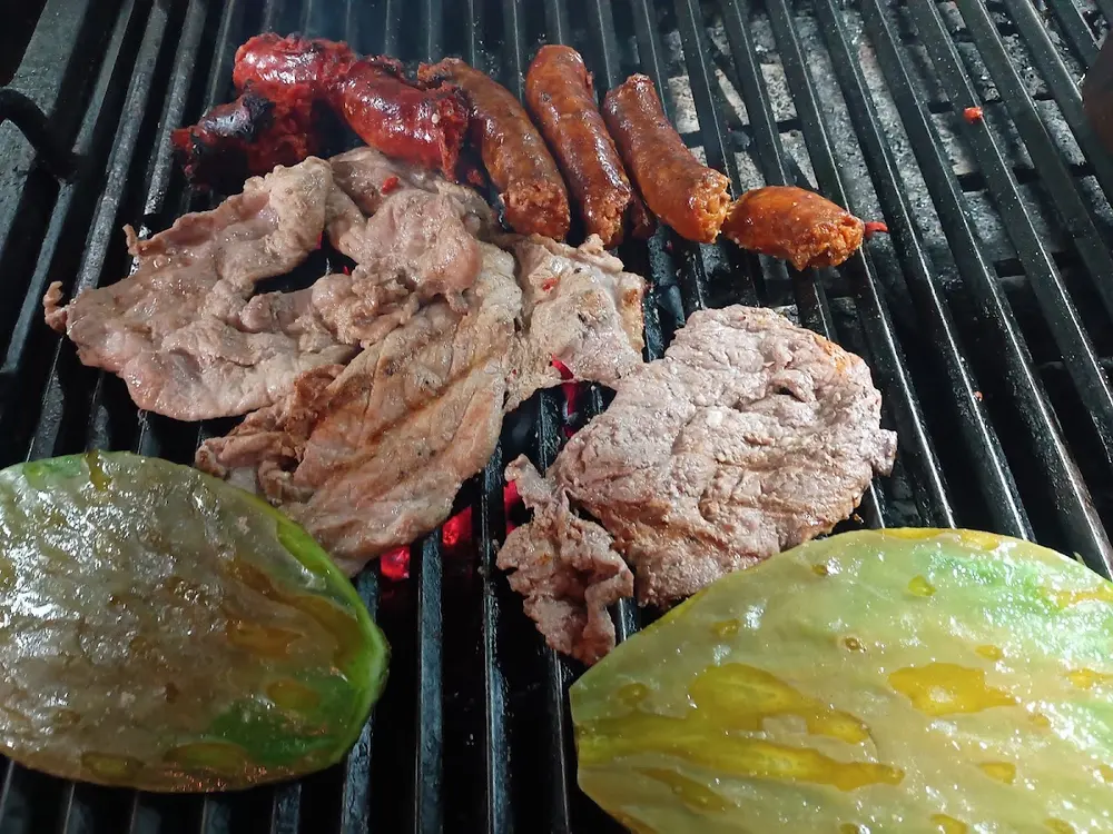 Carne asada, longaniza y nopales sobre la parrilla de carbón